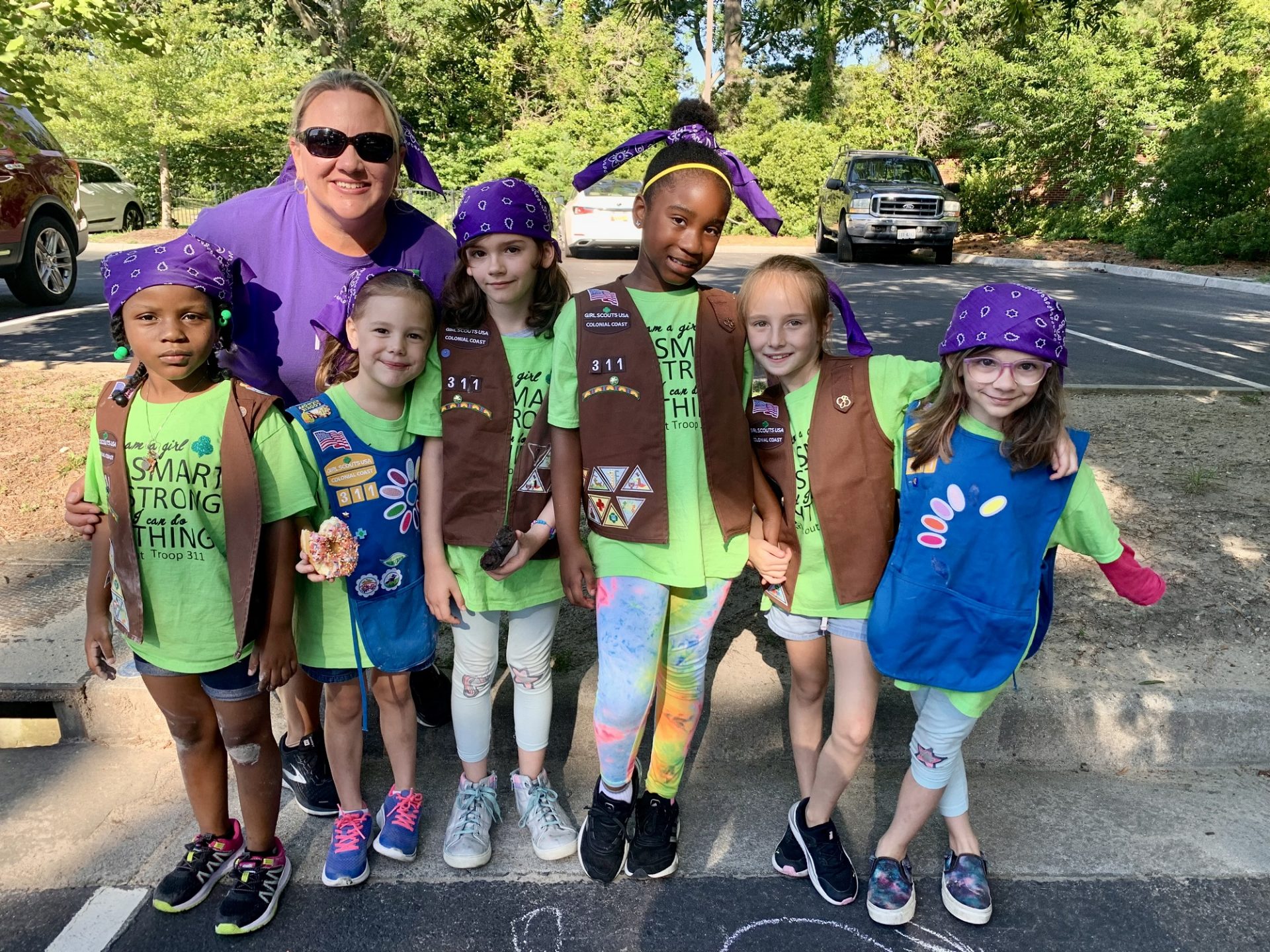 Girl Scout Daisies and Brownies with their troop leader posing for a photo outdoors at a charity run event