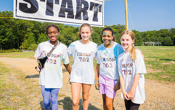 group of smiling Girl Scouts at the finish line of a color run event