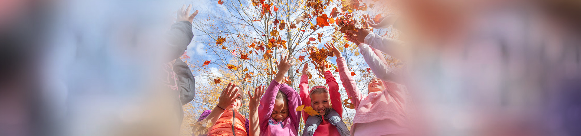  Girl Scouts outside in the fall throwing leaves and laughing 