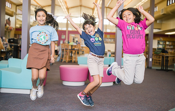 group of Girl Scouts laughing and jumping and playing indoors