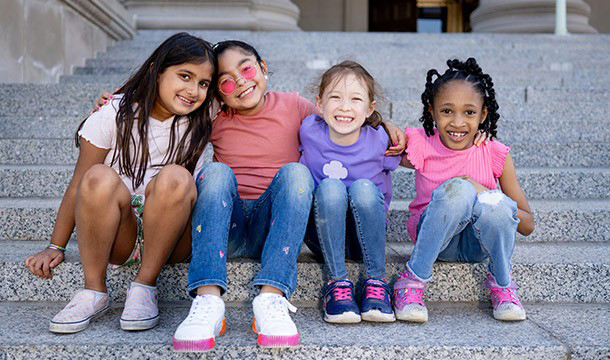 group of Girl Scouts sitting on steps outdoors and smiling