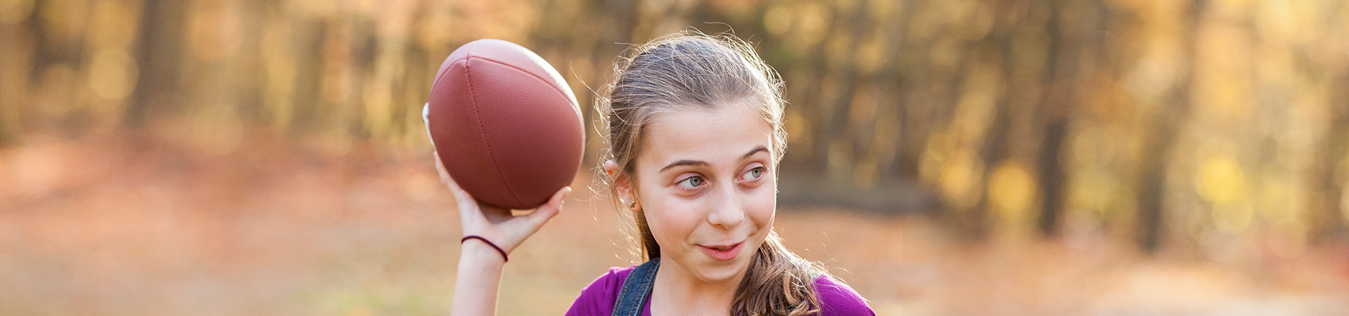  Girl Scout throwing a football outside in the fall 
