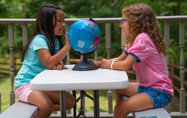 Girl Scouts sitting at a table looking at a globe