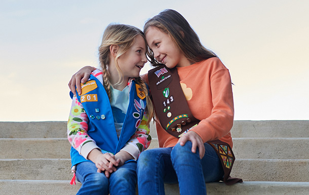 Girl Scout Daisy and a Girl Scout Brownie sitting outside together