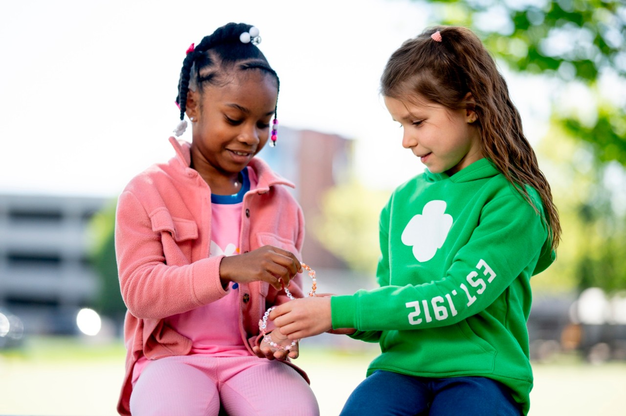 Girl Scouts sitting outside trading friendship bracelets