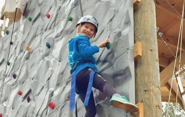 Girl Scout scales the outdoor climbing wall at Camp Darden