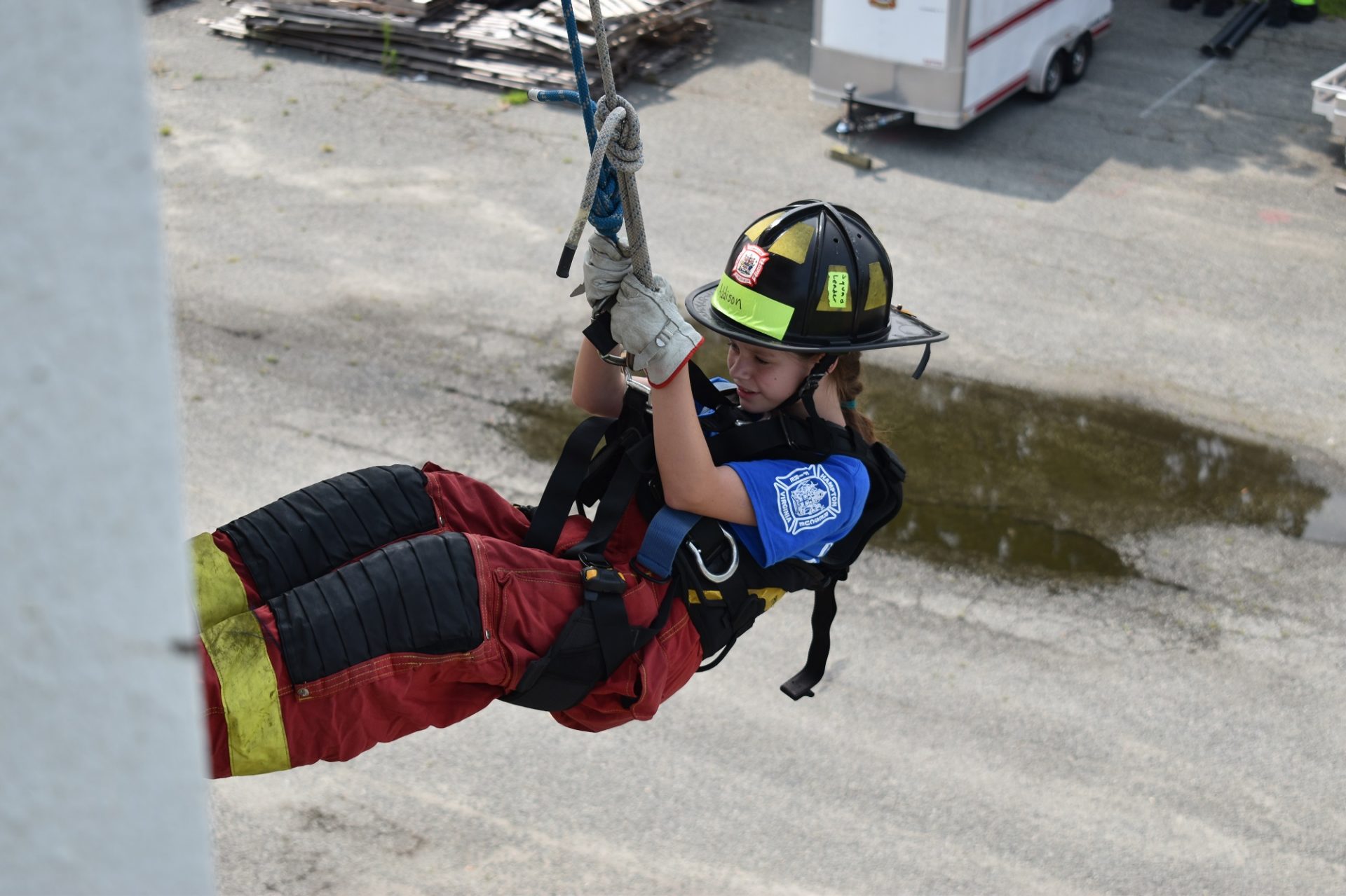Girl Scout in fire gear rappelling from a building at Camp Fury