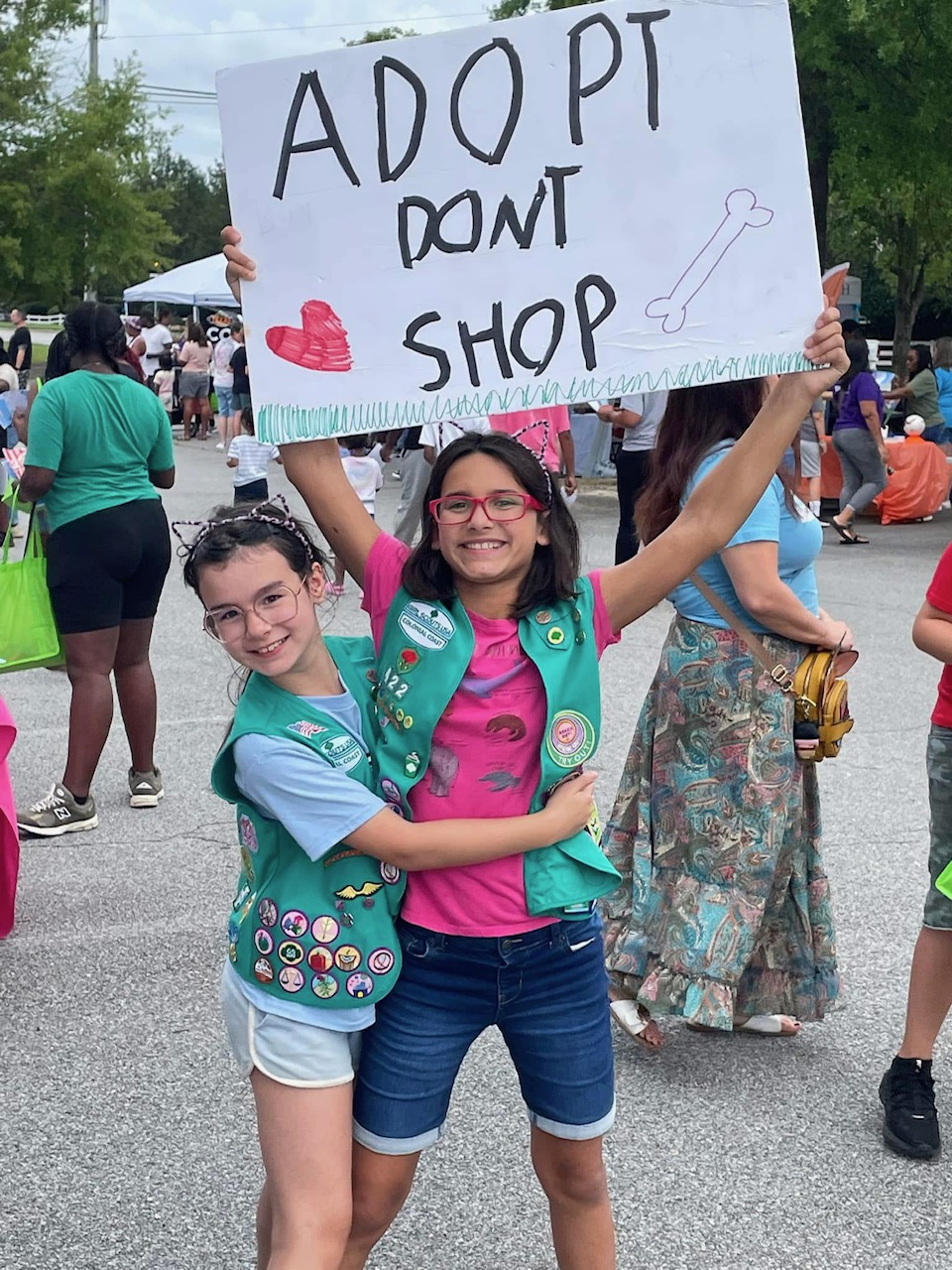 Girl Scout Juniors Evelyn and Lucy from Troop 422 in Suffolk holding a sign that reads, "Adopt Don't Shop"