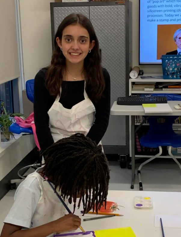 Girl Scout Ambassador Sarah helps a child with their art