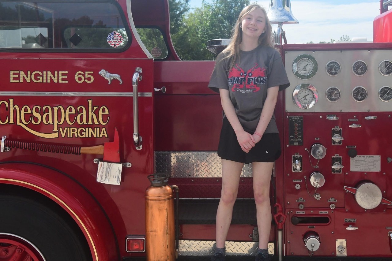 Girl Scout Senior Brianna standing on the deck of a fire engine