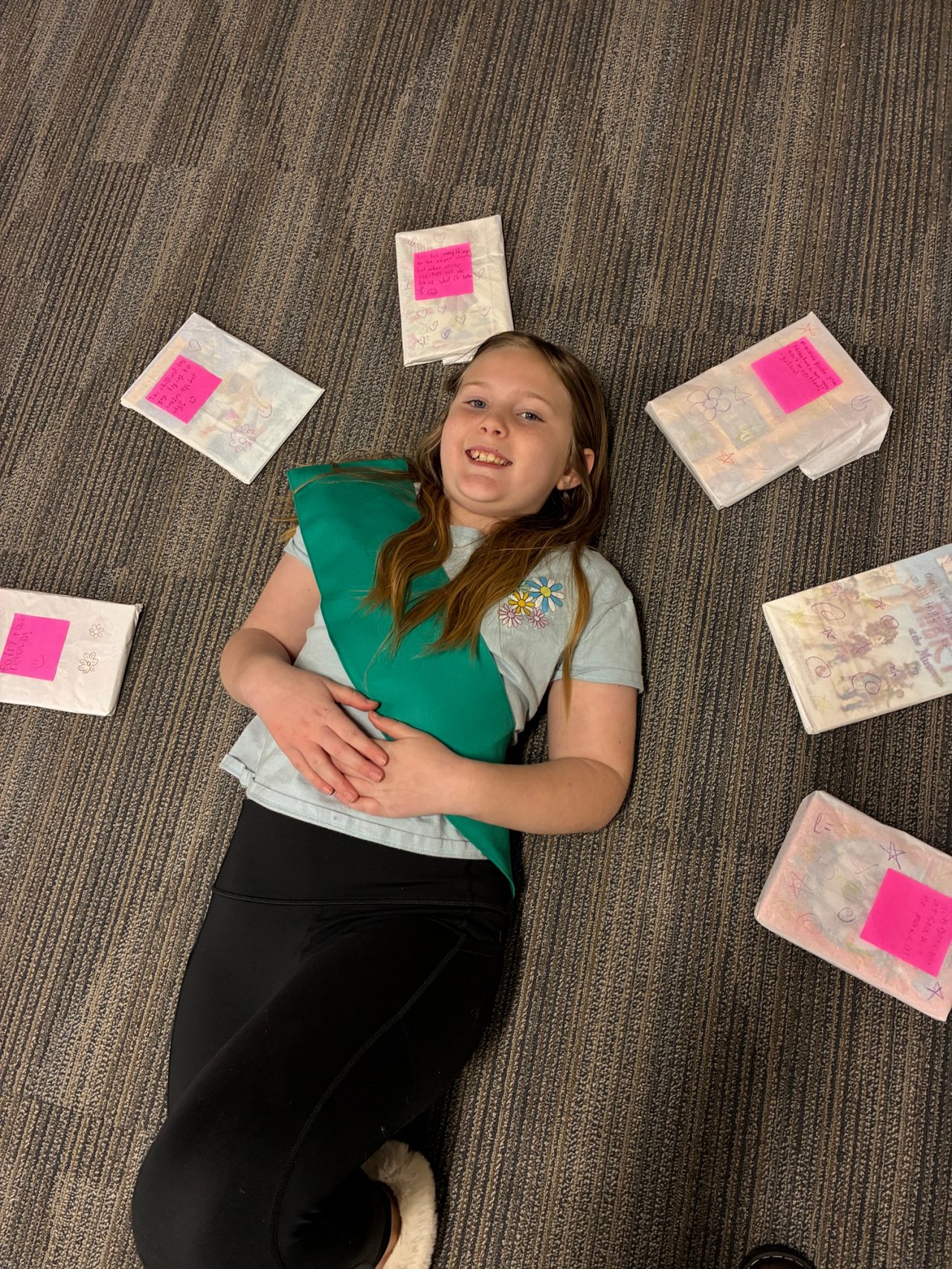 Girl Scout Junior poses for a photo with some of their wrapped “mystery books”