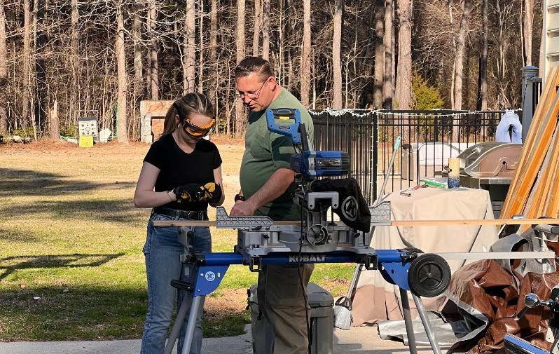 Lana gets help from a volunteer as she works with power tools