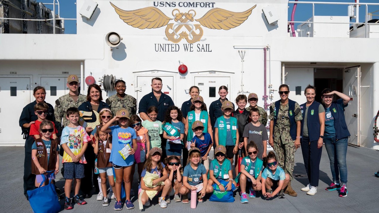 Terra Gray poses with Girl Scouts and other volunteers on the deck of the USS Comfort