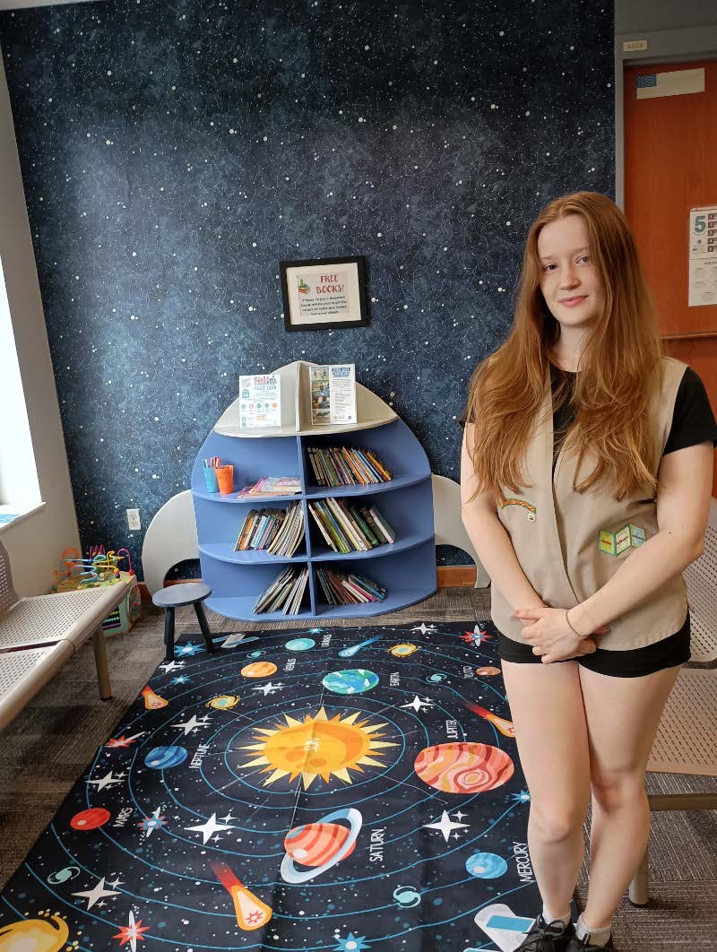 Girl Scout Nomi poses with her finished space-themed reading nook installation
