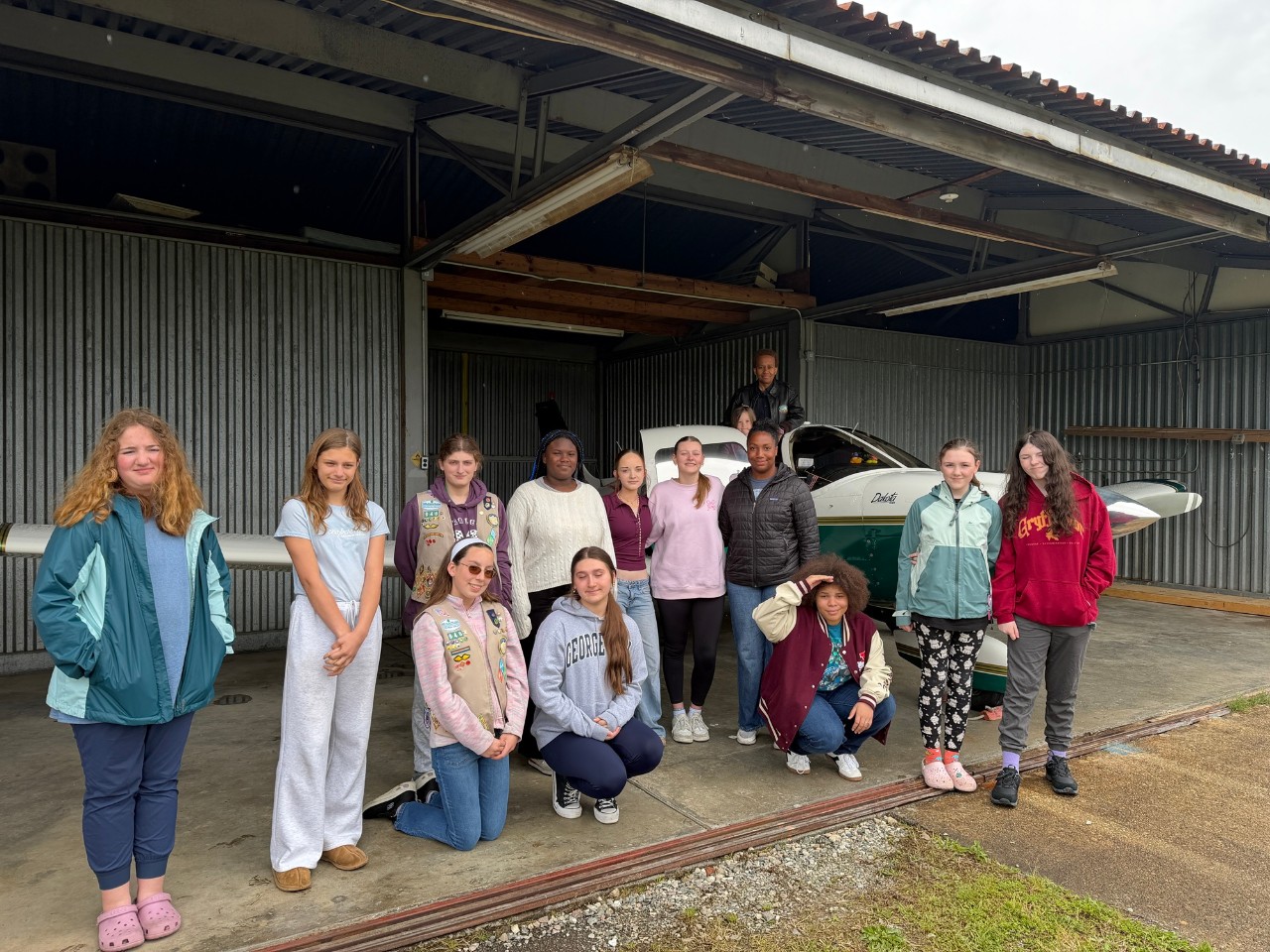 Girl Scouts pose by a plane with pilot Suzanne Collins