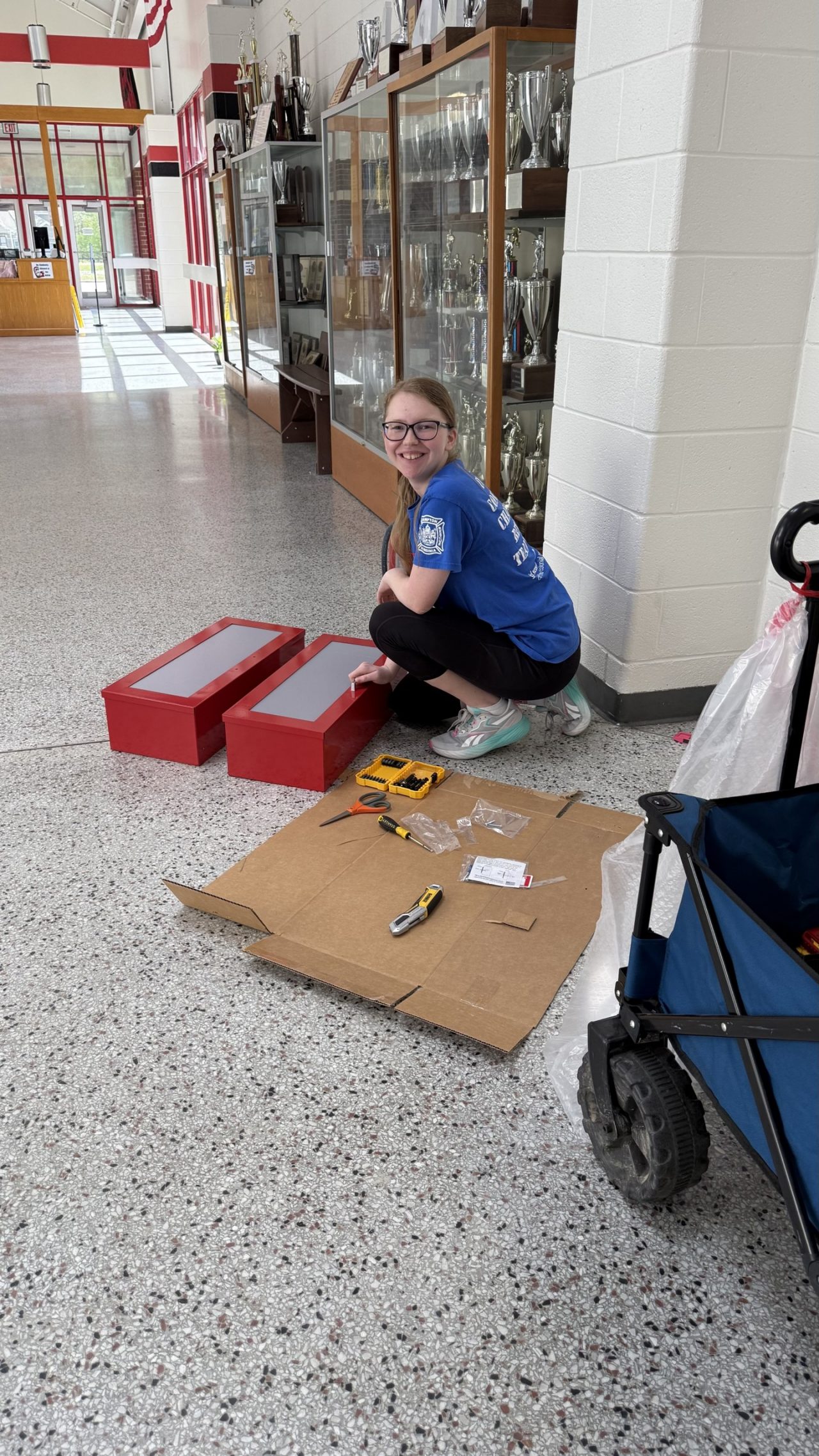 Gold Award Girl Scout Aliya prepares to install fire extinguisher cabinets at her school