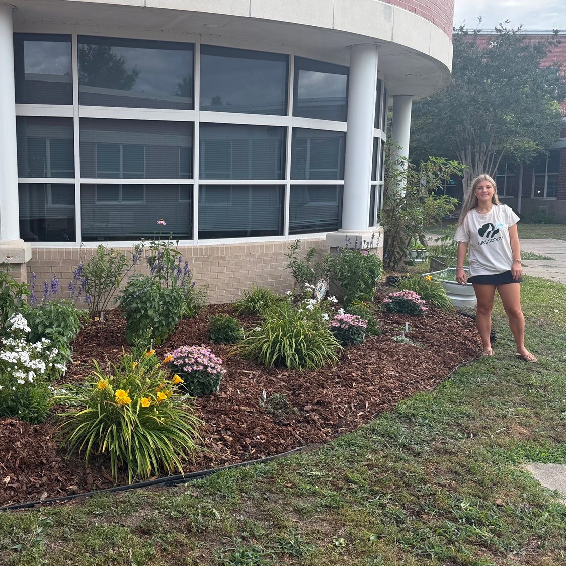 Girl Scout Madison poses next to her finished pollinator garden at Hickory Elementary School