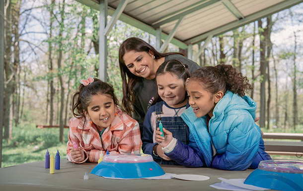 Girl Scouts working on a craft project with an adult volunteer