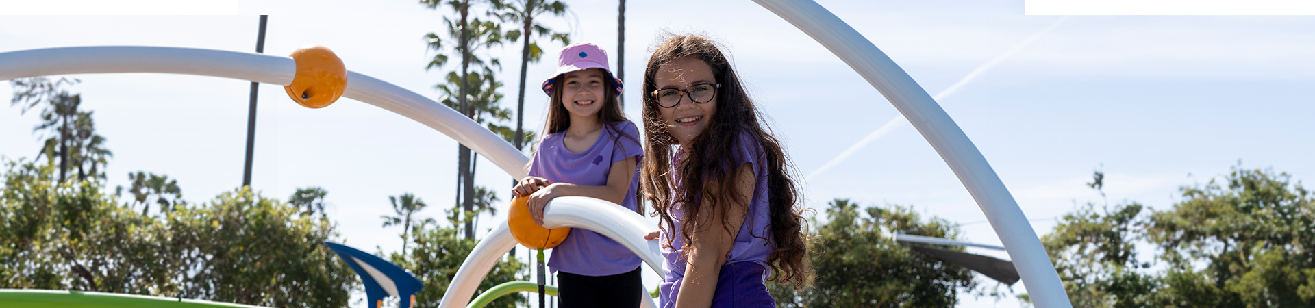  girls outside on a playground smiling 