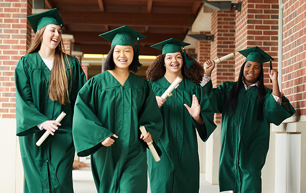 four high school graduates walking and smiling