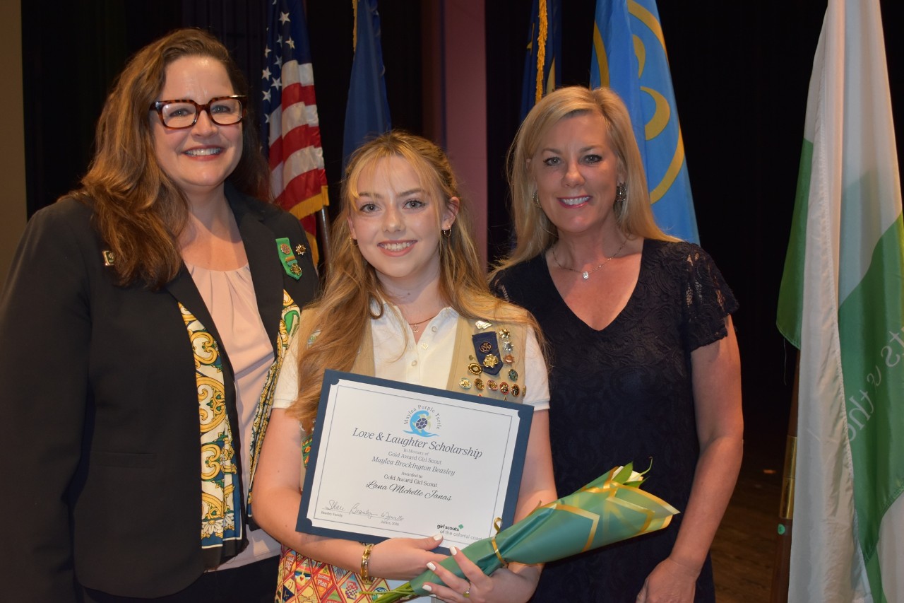 Girl Scout scholarship recipient at an awards ceremony with adult volunteers