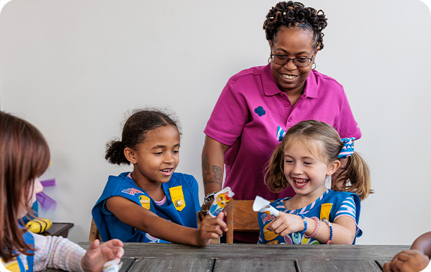 a troop leader helps Girl Scout Daisies with an activity