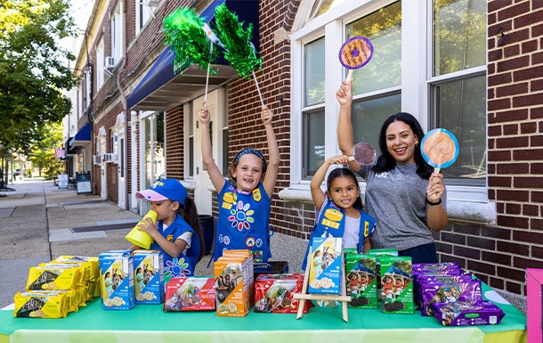 volunteer with Girl Scout Daisies at a cookie booth