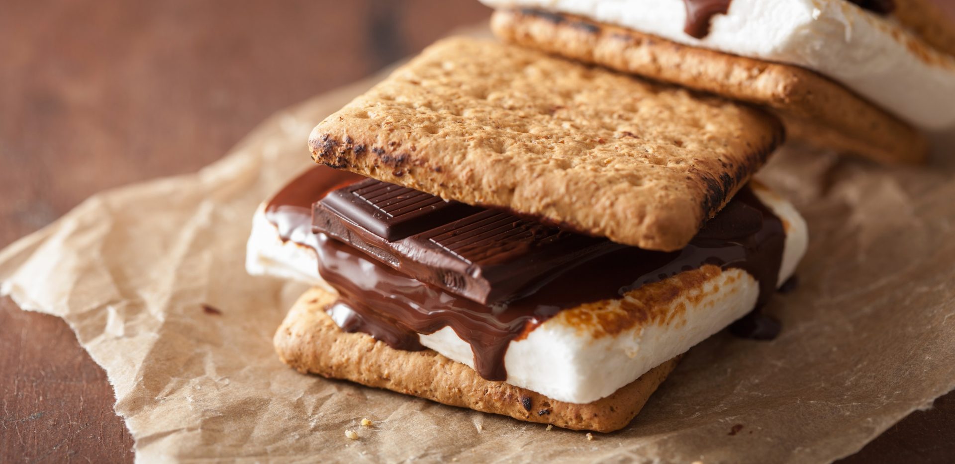 closeup of a gooey s’more on brown wax paper