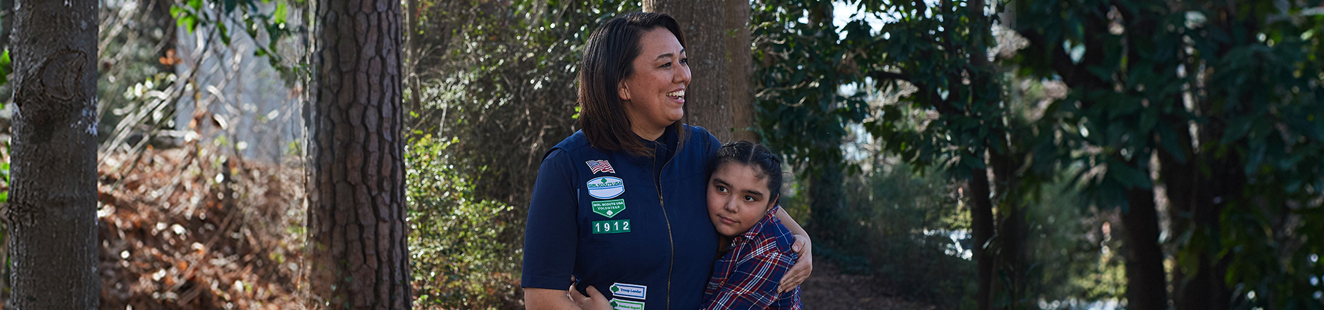  smiling adult volunteer with Girl Scout Junior outdoors 