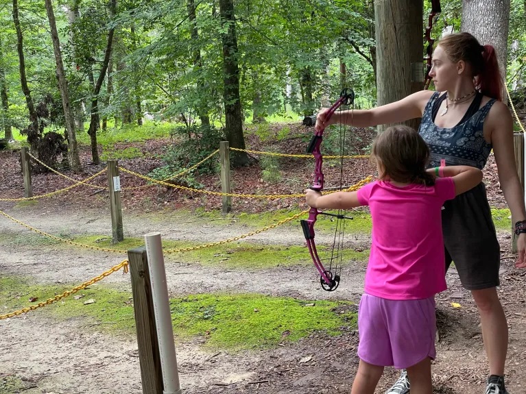 Julie Sekaninova helps a Girl Scout with archery at Camp Skimino.